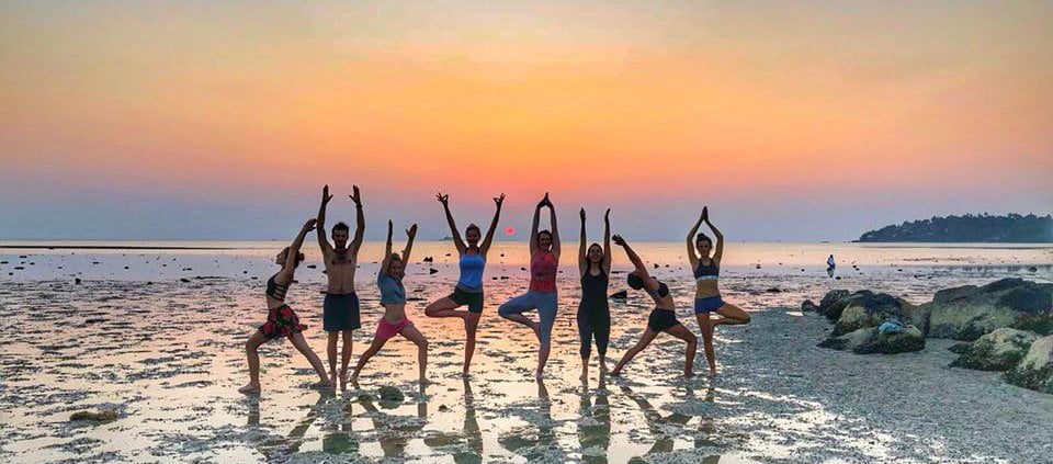 Happy yogis posing at the beach